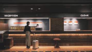 A reception area with a reception desk, a cloakroom, and a person with a suitcase.