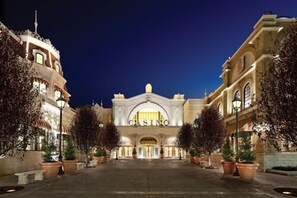 A grand building with a prominent entrance labeled "CASINO," flanked by symmetrical trees and well-lit by street lamps.