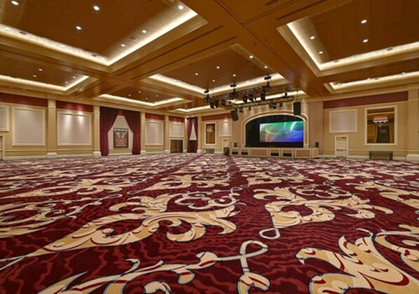 A large conference room with a red carpet, wooden ceiling, and a large screen at the front.