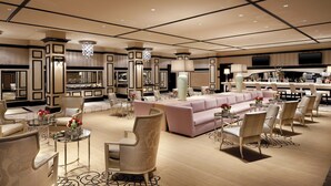 Een ruime hotellobby met een centraal zitgedeelte, meerdere fauteuils en een bar.