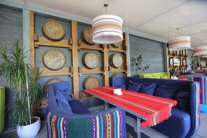 A cozy seating area with a wooden wall, a table with a red tablecloth, and striped hanging lamps. - Atlantic Garden Resort (Odesa)