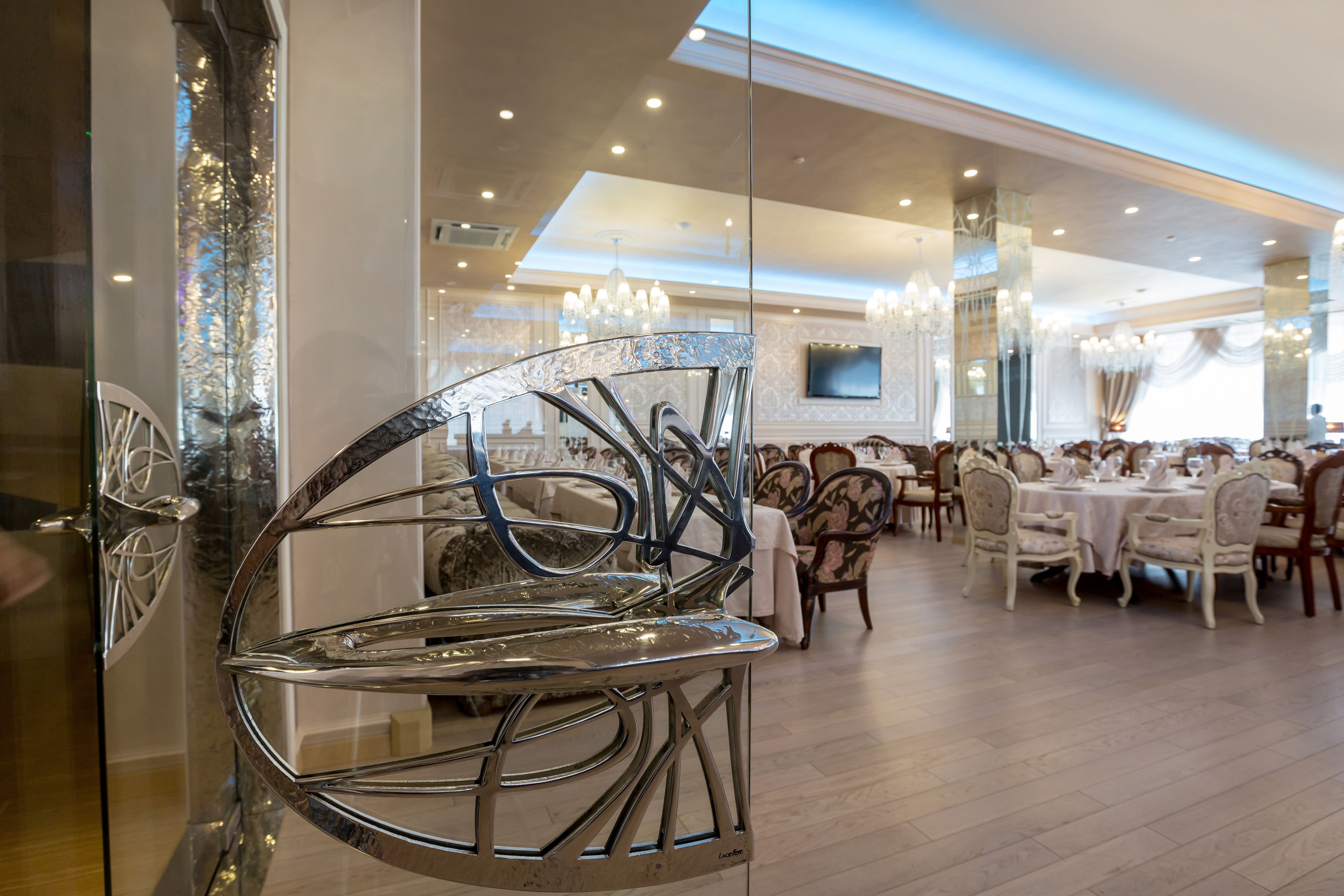Un comedor moderno con una silla de metal original, elegantes candelabros y mesas de comedor clásicas.