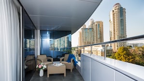 Ein Balkon mit Korbmöbeln, einem Blumenstrauß und Blick auf die Stadt.