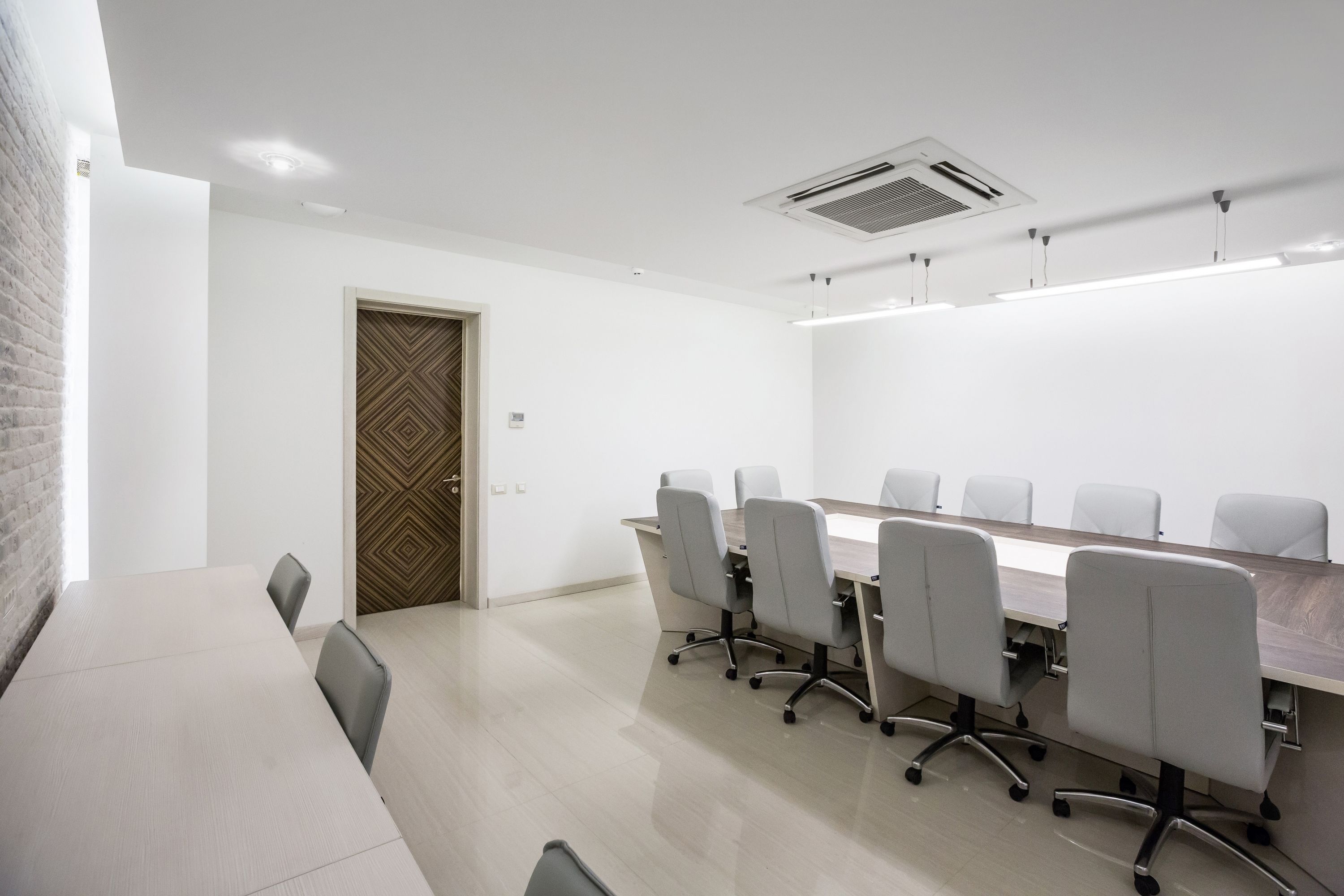 A conference room with a long table, six chairs, and a patterned door.