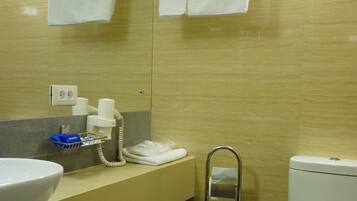 Un baño con lavabo, espejo, toallero, inodoro y cubo de basura.