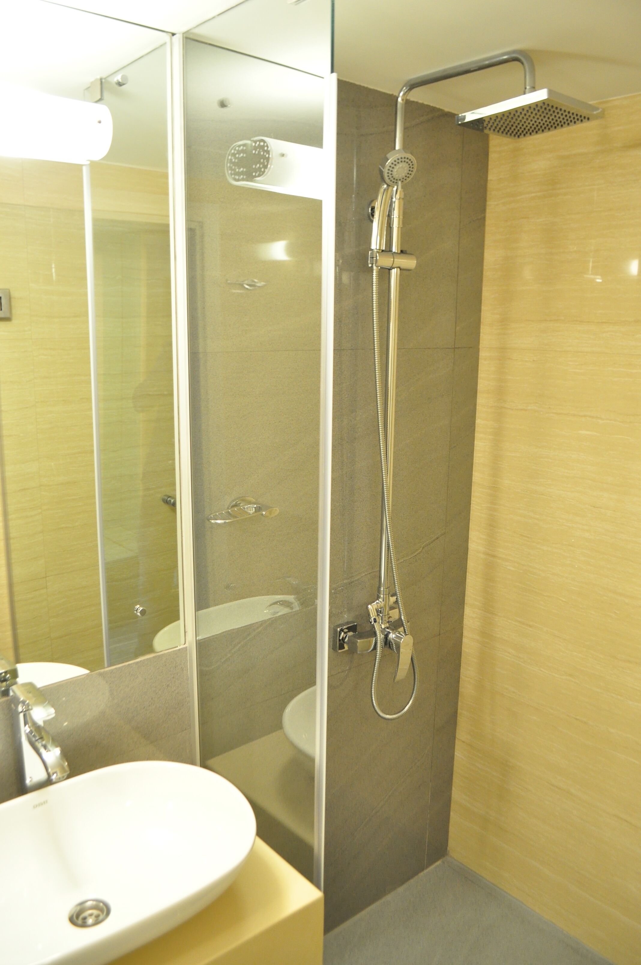 Un baño moderno con ducha de vidrio, lavabo blanco y espejo.