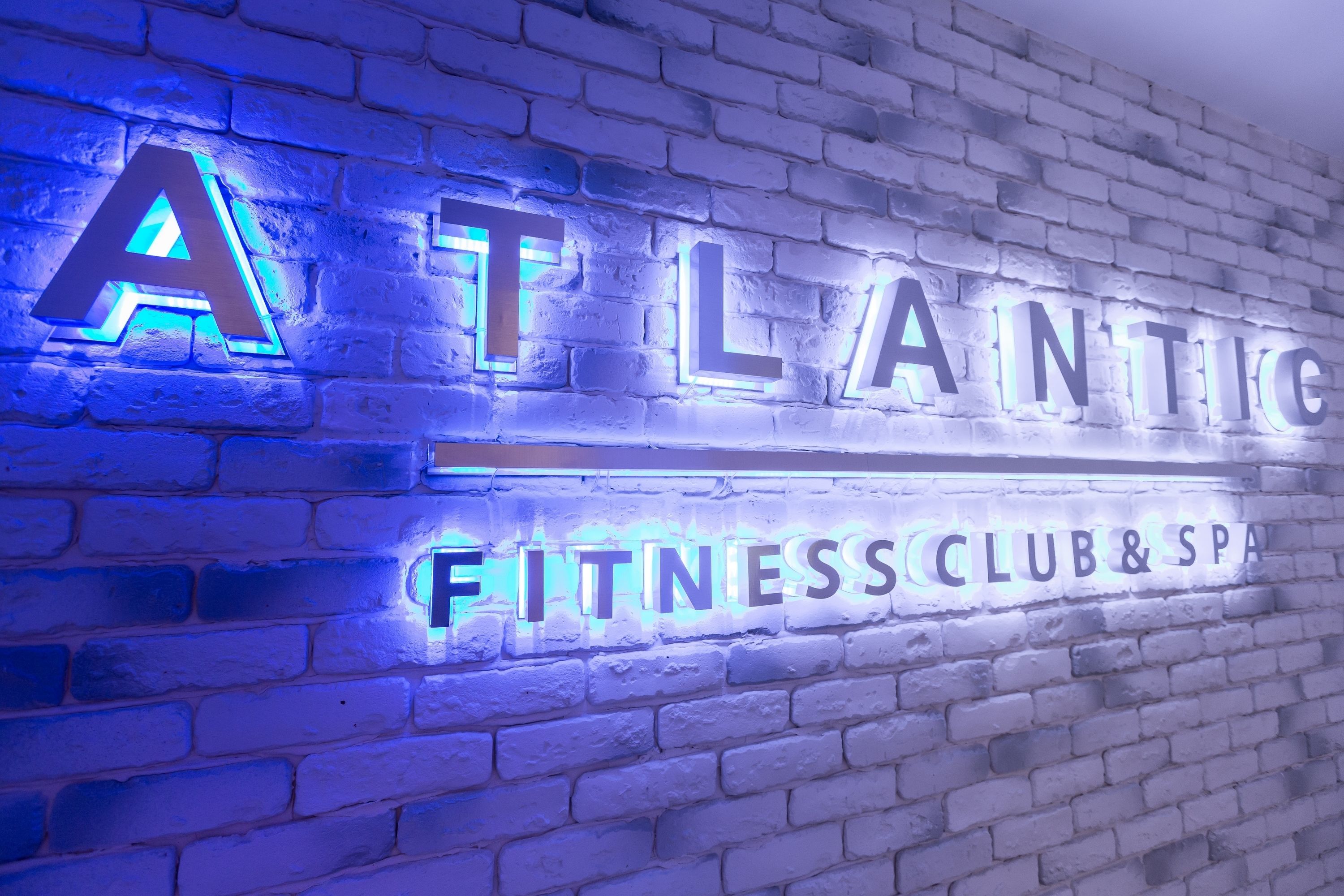 Pared de ladrillo con letras iluminadas que dicen "ATLANTIC FITNESS CLUB & SPA".
