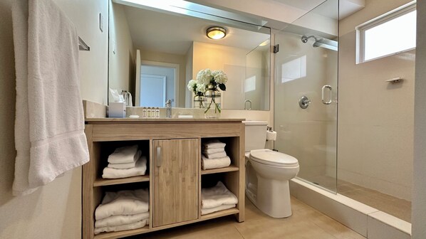 A modern bathroom with a wooden vanity, a glass shower enclosure, and a large mirror.