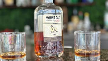 Une bouteille de rhum Mount Gay et deux verres sur le comptoir d’un bar.