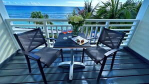 Een balkon met twee stoelen, een tafel en een bloevas.