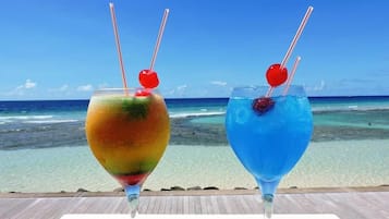 Two cocktails on a table with a view of the ocean.