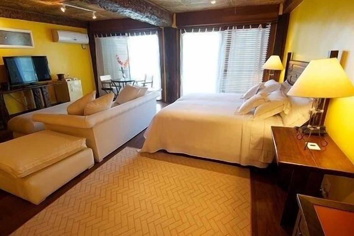 A hotel room with a bed, a sofa, a desk, and a television.