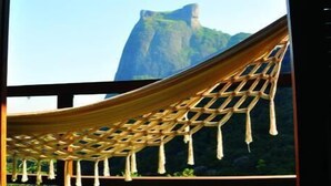 A hammock tied between two windows with a view of a mountain. - TuAkAzA Exclusive Boutique Lodge (Rio de Janeiro)