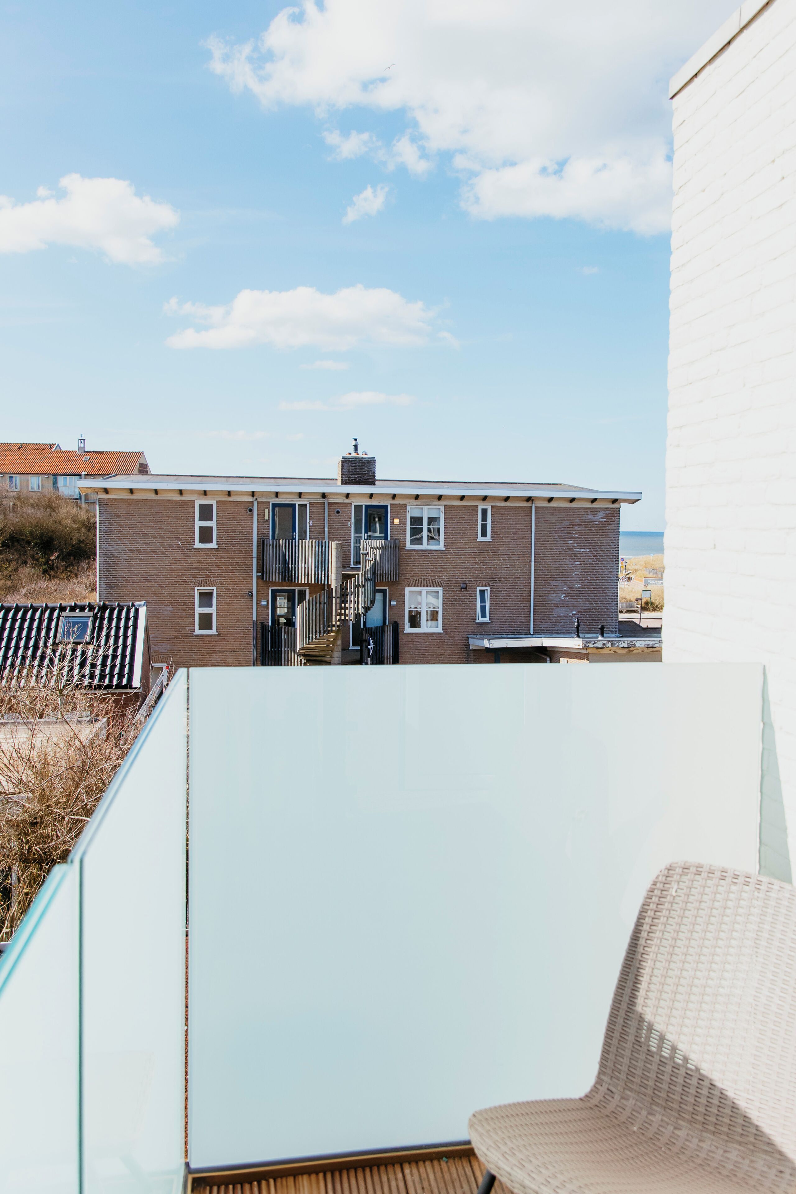 A building with a brick facade, a staircase leading to a door, and a view of the sky.