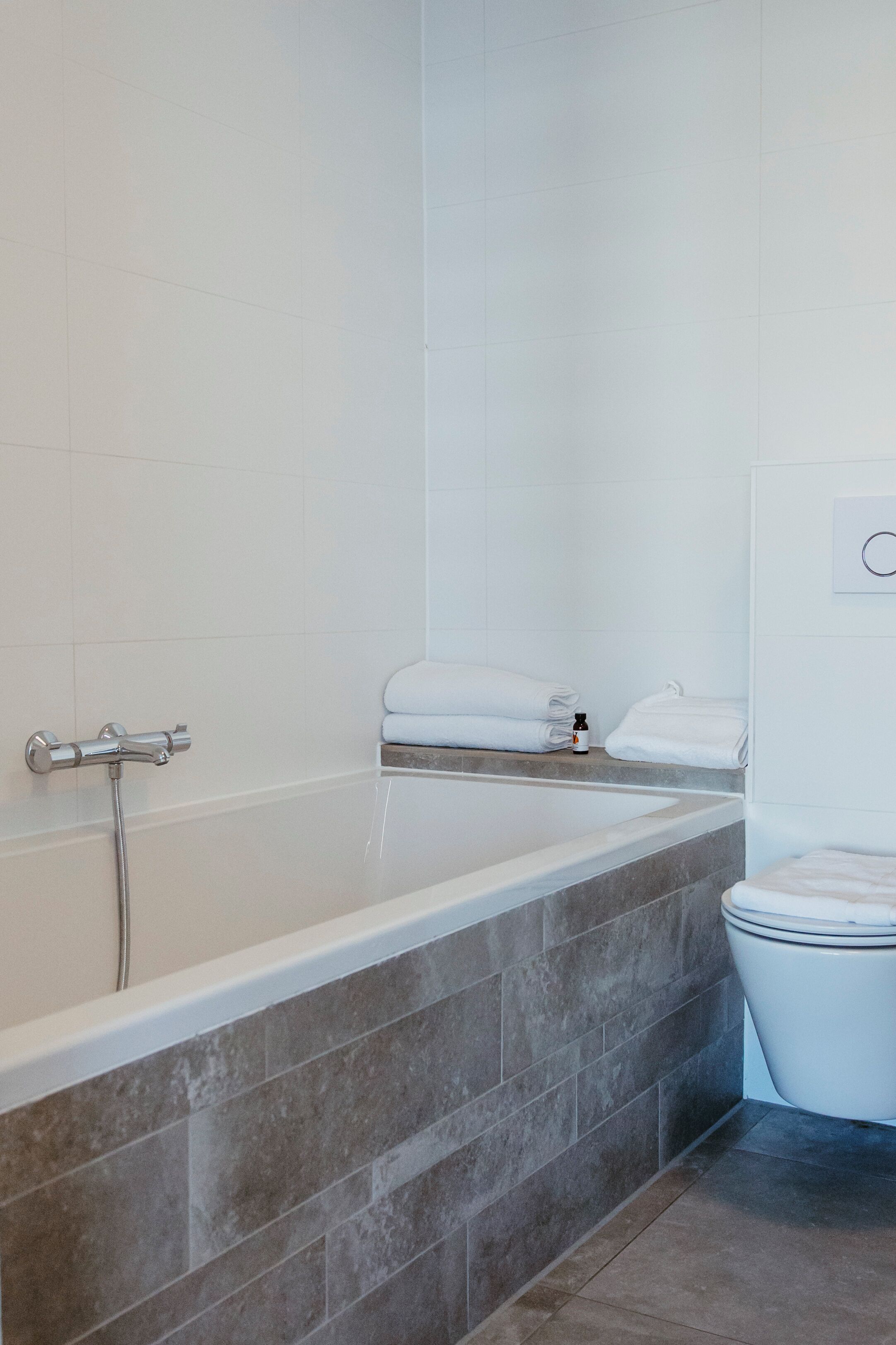 A modern bathroom with a bathtub, a toilet, and a towel rack.