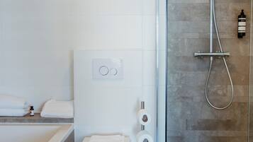 Un baño moderno con ducha de vidrio, inodoro blanco y bañera.