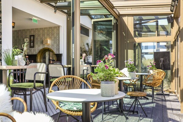 Un patio al aire libre con sillas de mimbre, una mesa redonda y plantas en macetas.