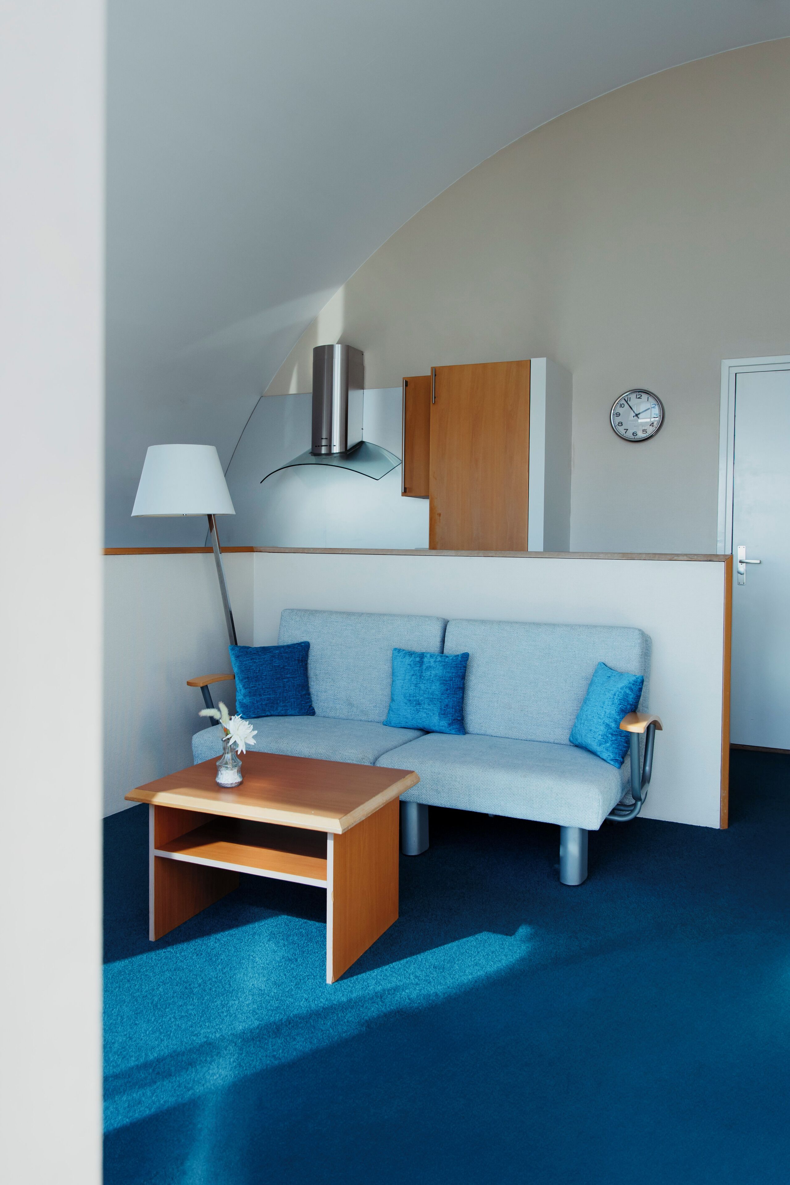 Un espace de vie compact comprenant un canapé, une petite table et une lampe.