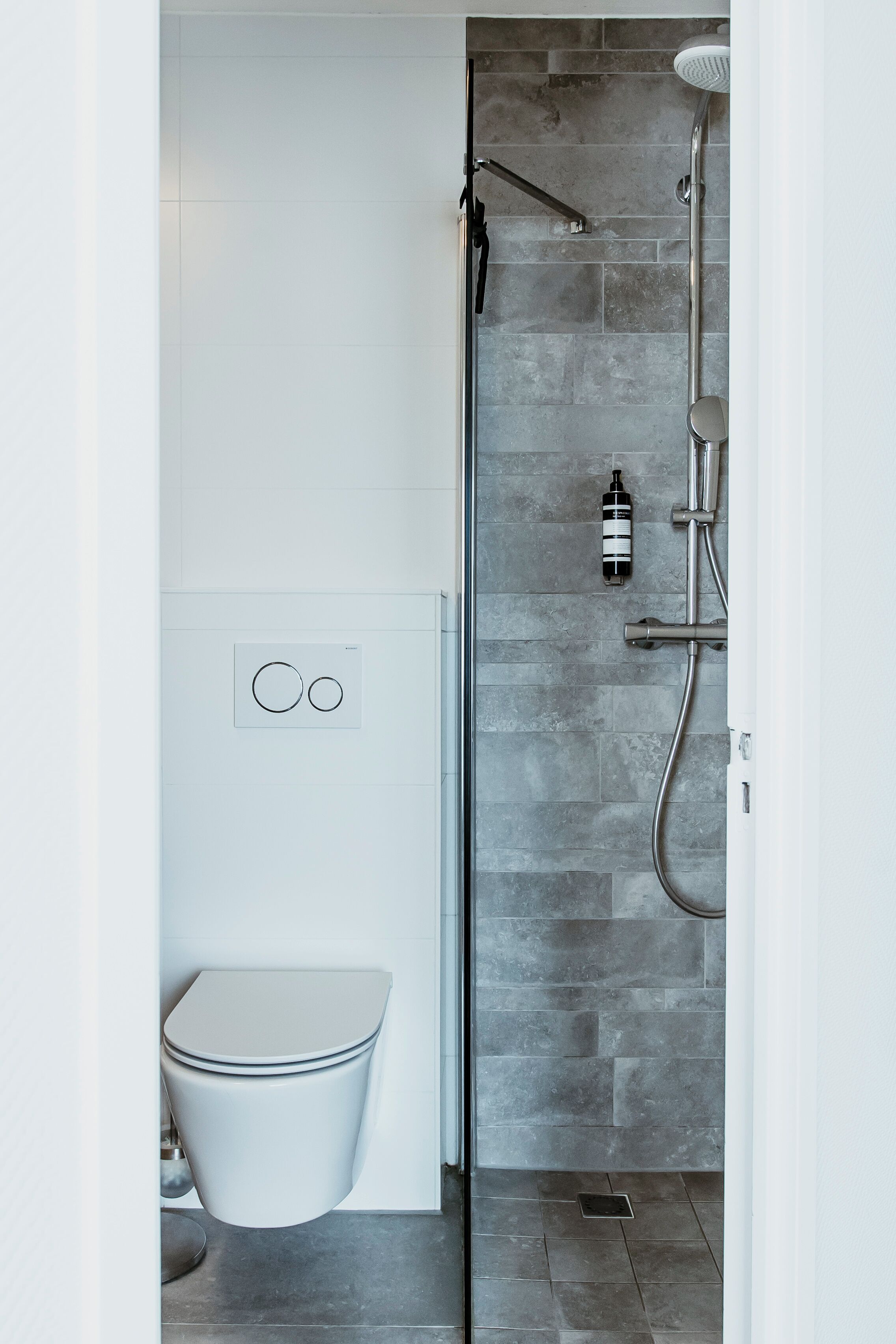Une salle de bain moderne équipée d’une douche, de toilettes et d’un panneau de commande fixé au mur.