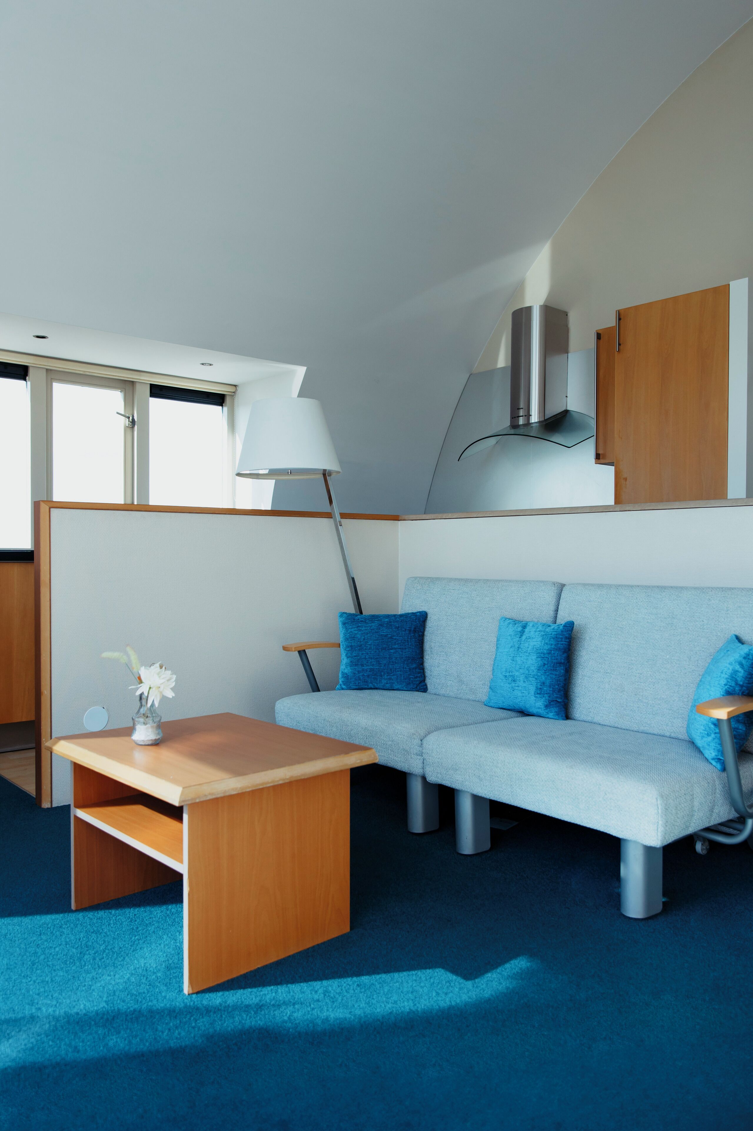 Un interior moderno con un sofá azul claro, una mesa de centro de madera y una lámpara.