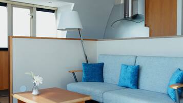 Een modern interieur met een lichtblauwe bank, een houten bijzettafeltje en een lamp.