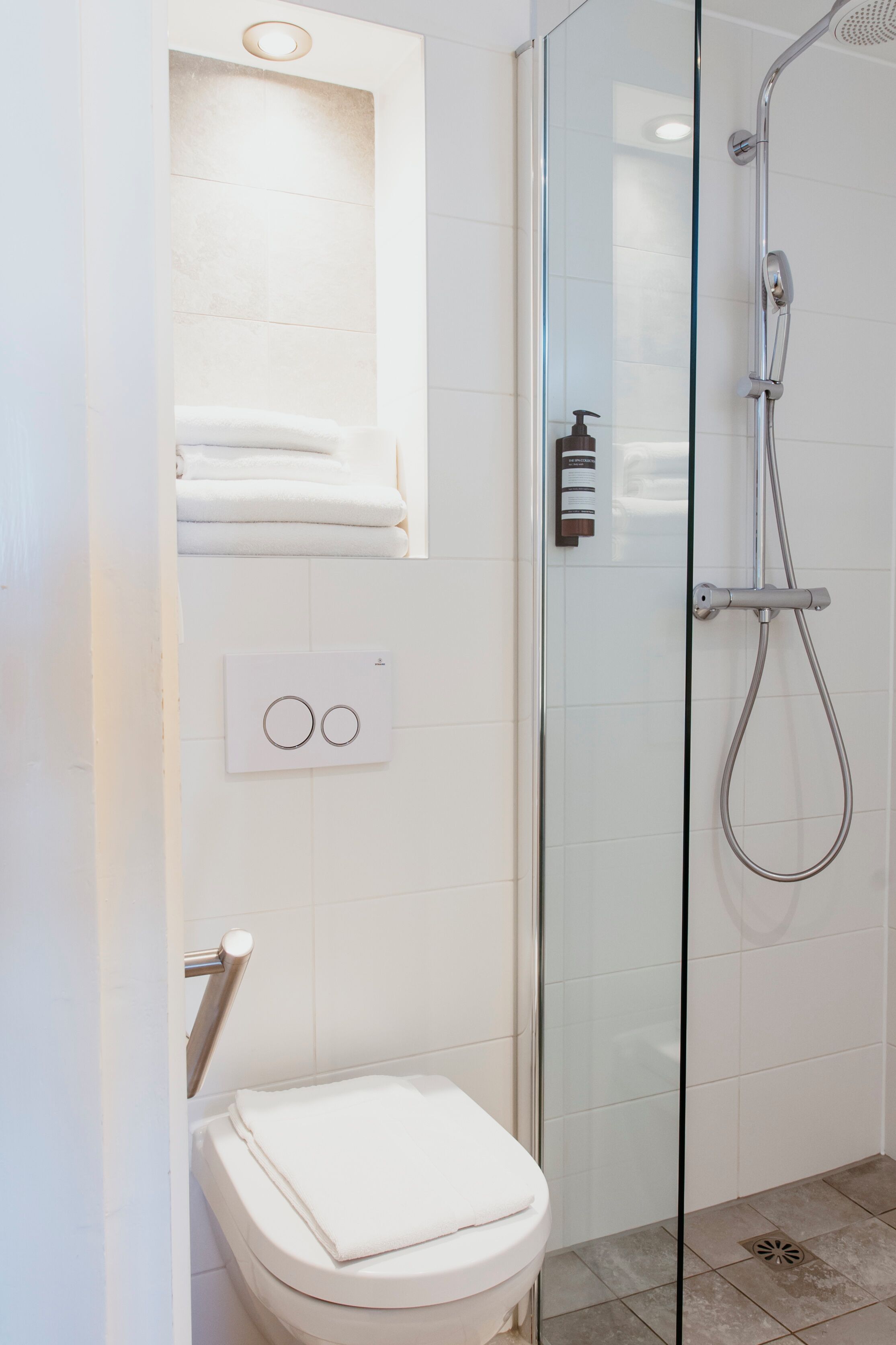 Une salle de bain moderne avec une douche à parois de verre, des toilettes et un porte-serviettes.