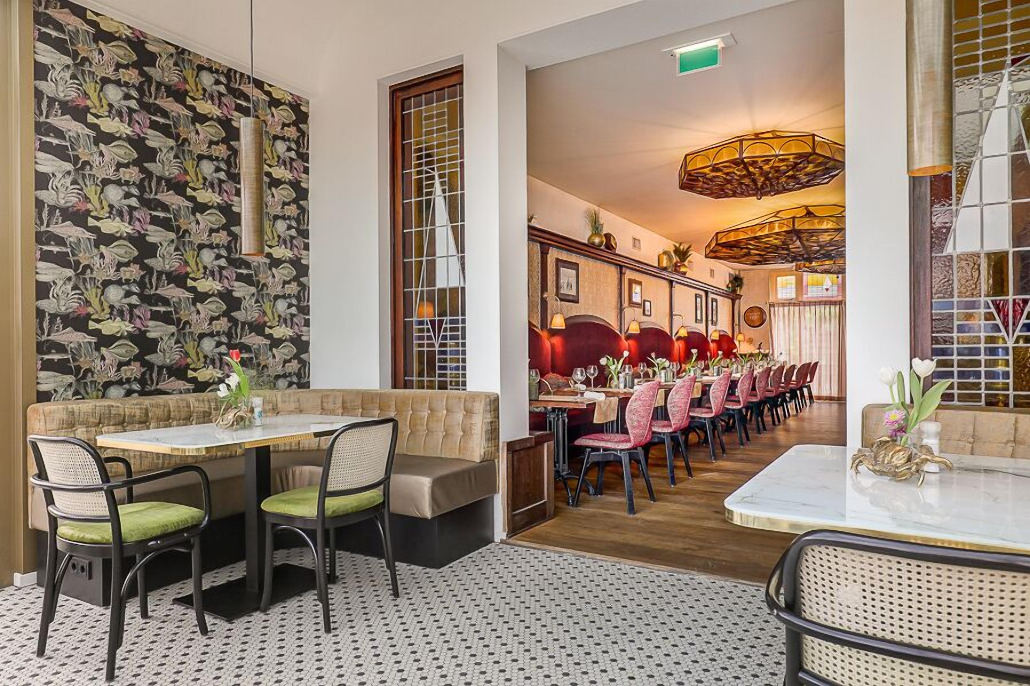 A restaurant with a long dining table, cushioned seating, and a patterned wall.