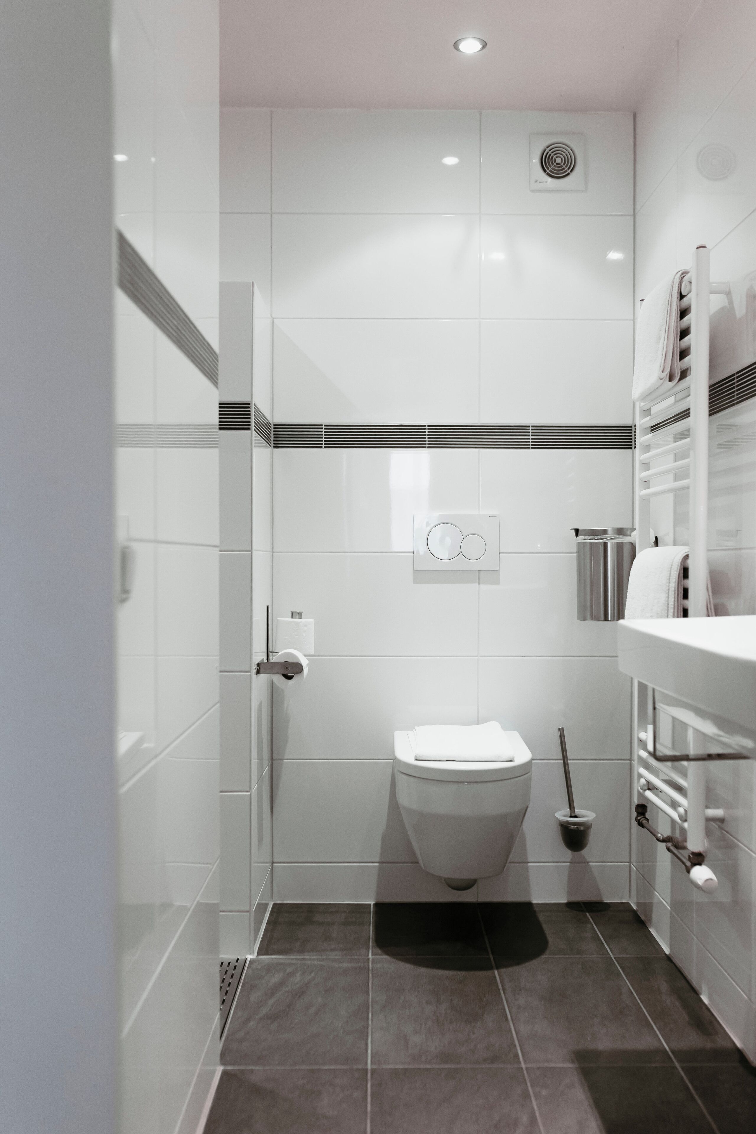A modern bathroom with a toilet, bidet, and a towel rack.