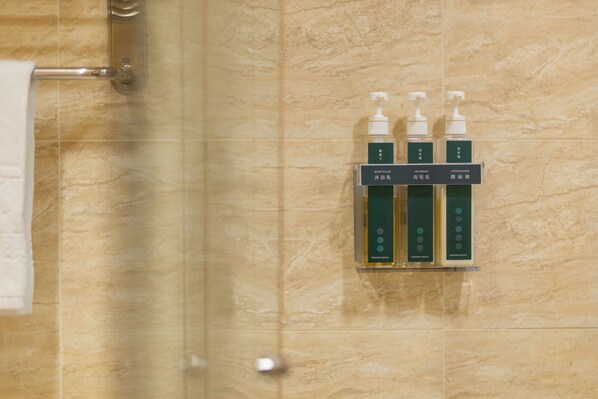 A bathroom with a shower area and a shelf holding three bottles of toiletries labeled 'BODY WASH,' 'SHAMPOO,' and 'CONDITIONER.' - Kindness Hotel Glory Pier (Kaohsiung)