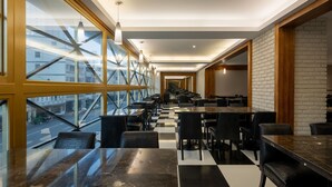 A modern restaurant with a checkered floor, black and white walls, and large windows offering a view of the street. - Kindness Hotel Glory Pier (Kaohsiung)