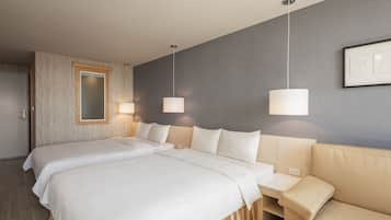 Ein Hotelzimmer mit zwei Betten, einem Sofa und einem großen Spiegel.