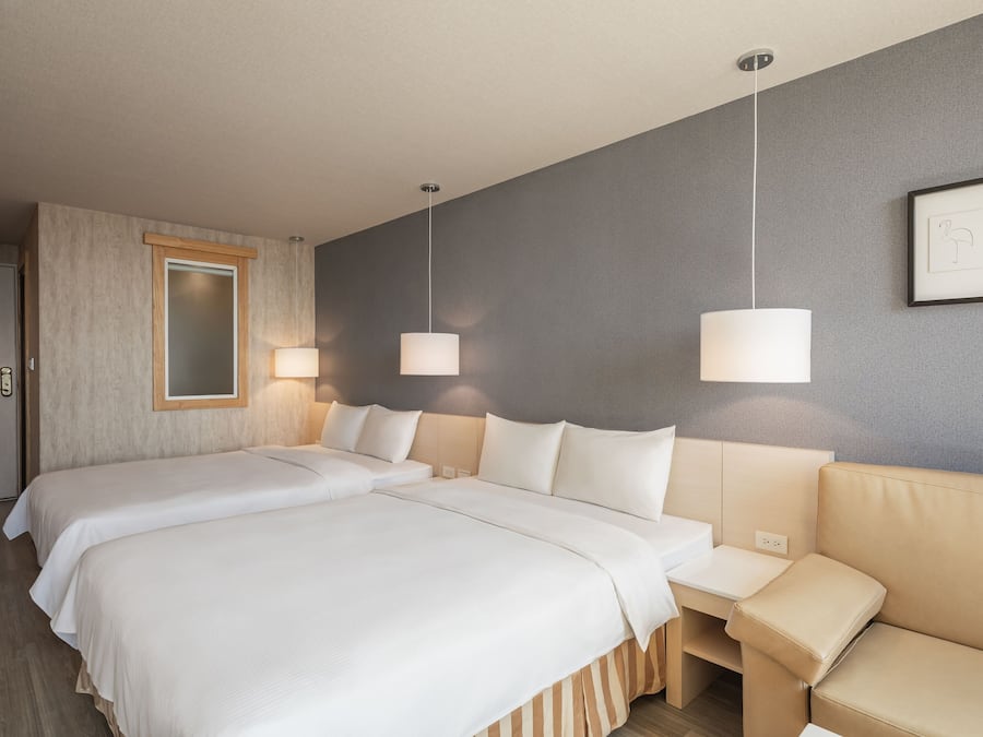 Ein Hotelzimmer mit zwei Betten, einem Sofa und einem großen Spiegel.