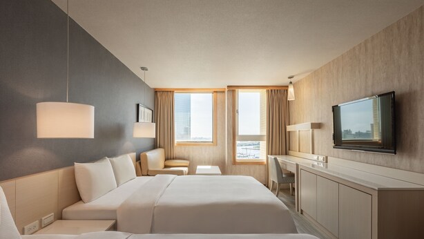 A hotel room with two beds, a desk, a chair, and a TV. - Kindness Hotel Glory Pier (Kaohsiung)
