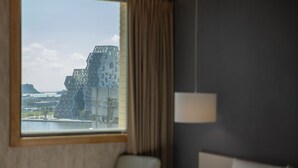 A hotel room with a large window offering a view of a modern building and a body of water. - Kindness Hotel Glory Pier (Kaohsiung)
