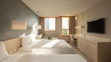 Una habitación de hotel con una cama grande, un escritorio, un televisor y una ventana con cortinas.