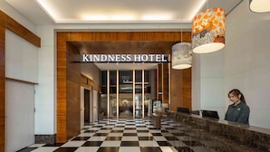A hotel lobby with a checkered floor, a reception desk, and a sign reading "Kindness Hotel". - Kindness Hotel Glory Pier (Kaohsiung)