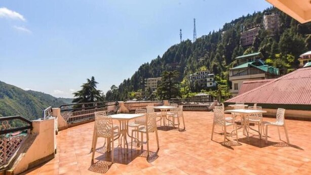 A terrace with outdoor seating and a view of a mountainous landscape. - Anand Palace Hotel (Udaipur)