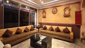 A modern living room with two sofas facing a glass wall, a marble coffee table, and decorative wall art. - Anand Palace Hotel (Udaipur)