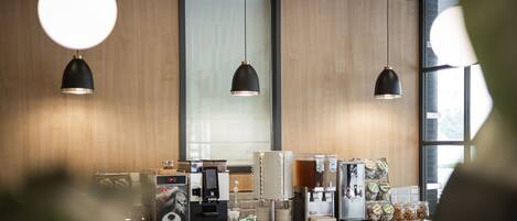 Interior moderno de café com paredes de madeira, iluminação pendente e balcão de café equipado com diversas máquinas e dispensadores de café.