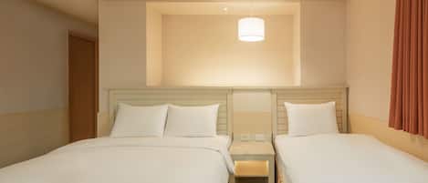 Habitación de hotel con dos camas, una mesita de noche, una lámpara y una ventana con cortinas.