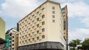 Ein mehrstöckiges Hotel mit beige farbenem Fassadengestalt, zahlreichen Fenstern und einem Schild, das es als Hotel kennzeichnet.