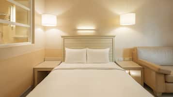 Una camera d'albergo con un letto, comodini, una lampada e una finestra.