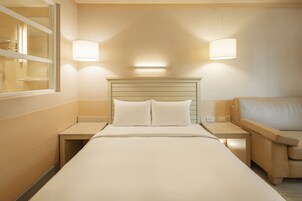 Una camera d'albergo con un letto, comodini, una lampada e una finestra.