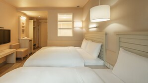 Ein Hotelzimmer mit zwei Betten, einem Fernseher, einem Schreibtisch und einem Fenster.