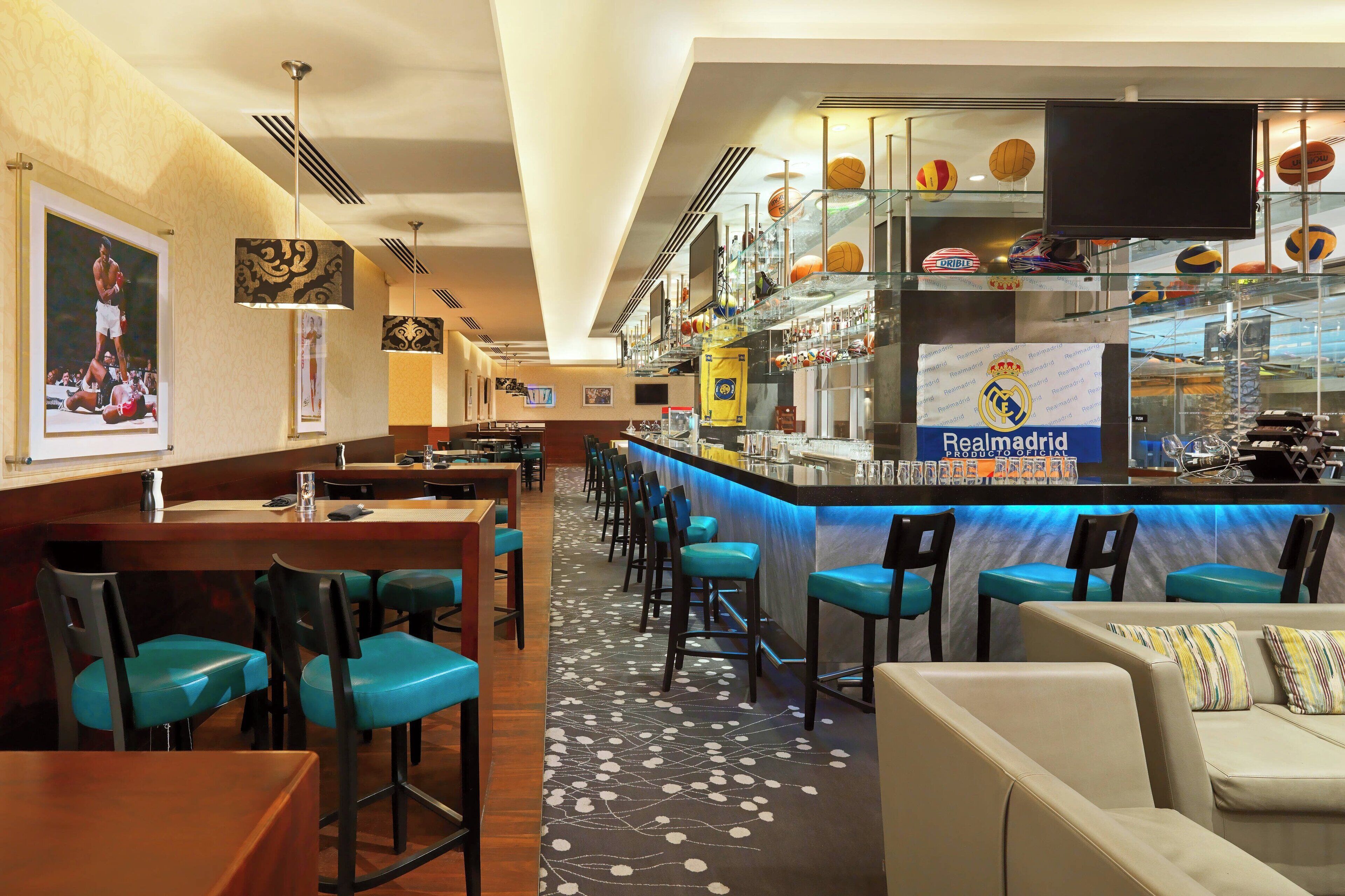 Zona de bar con mostrador, taburetes y un espacio de estar con sillas y un sofá.