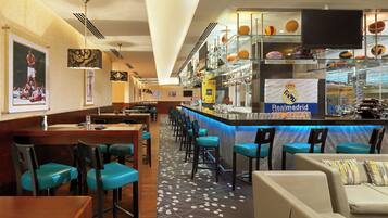 A bar area with a counter, bar stools, and a seating area with chairs and a sofa.