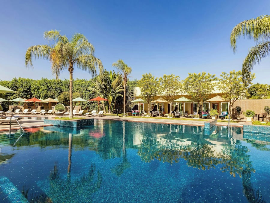 Una piscina al aire libre, camas de piscina con cargo, sombrillas