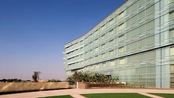 A modern building with a glass facade, labeled 'MERIDIAN,' featuring a landscaped courtyard with pathways and greenery.