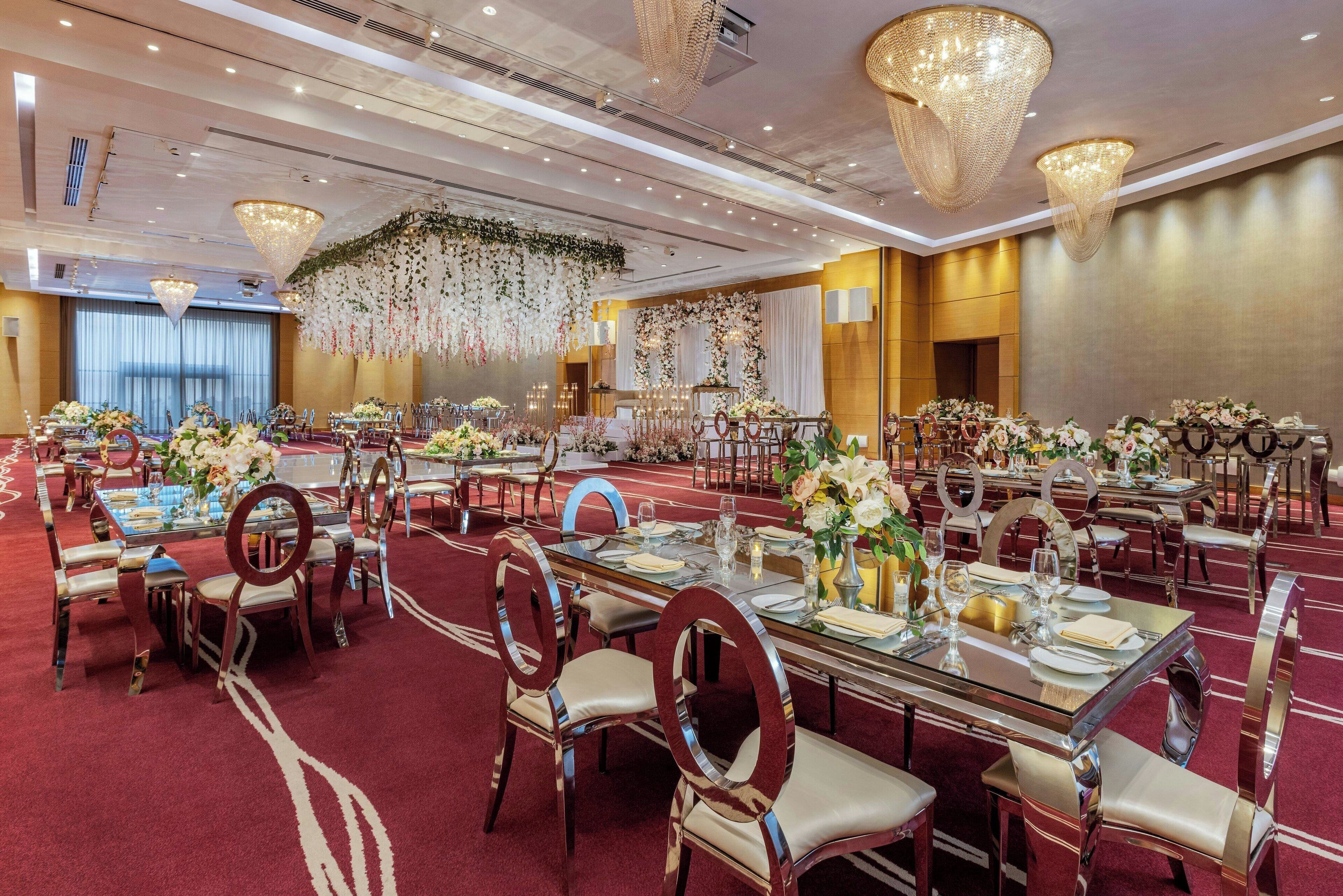 A banquet hall with multiple round tables, each set with chairs and floral centerpieces.