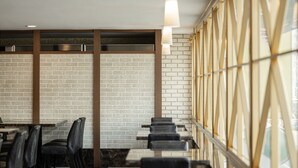 L’intérieur d’un restaurant avec des murs en briques, des chaises en cuir noir et un sol à carreaux.